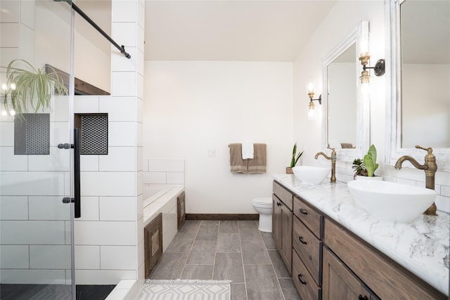 bathroom with double vanity, a stall shower, tiled bath, and a sink