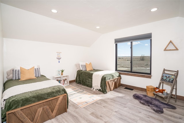 bedroom with visible vents, baseboards, lofted ceiling, and wood finished floors