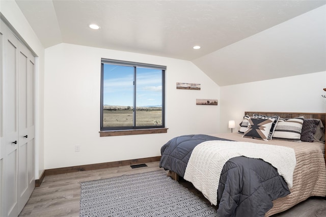 bedroom with lofted ceiling, wood finished floors, and baseboards