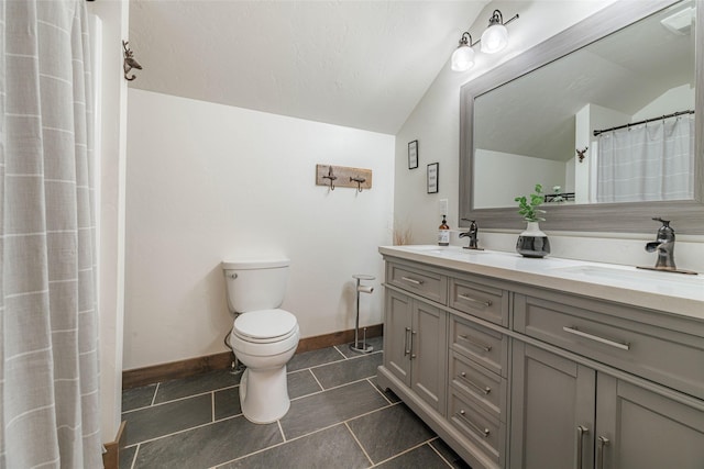 bathroom with a sink, lofted ceiling, toilet, and double vanity