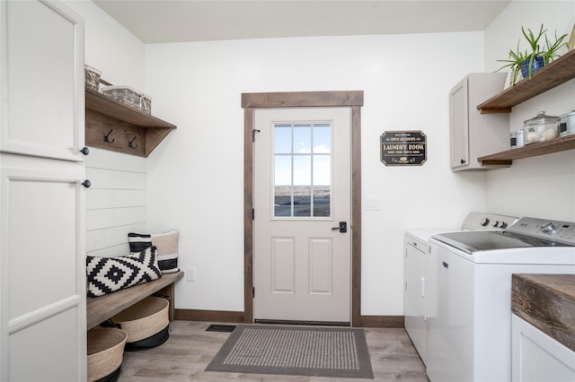 washroom with separate washer and dryer, cabinet space, light wood-type flooring, and baseboards