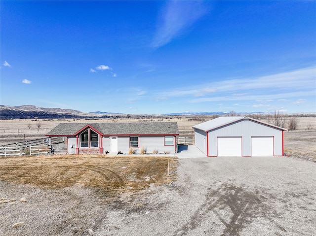 view of front of home featuring a detached garage, fence, a mountain view, and an outbuilding