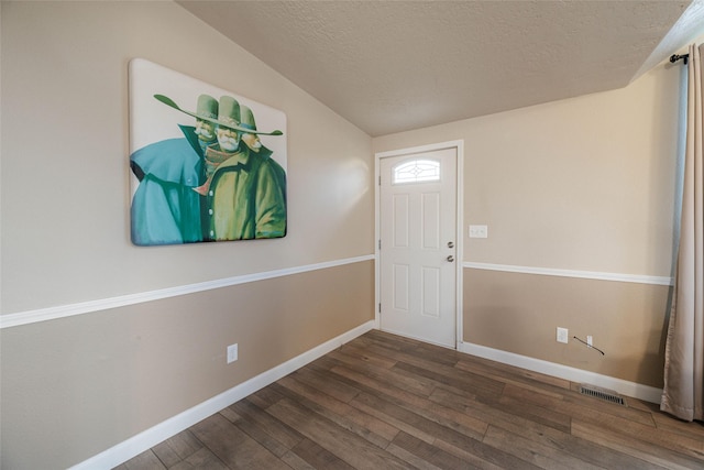 foyer entrance featuring visible vents, lofted ceiling, a textured ceiling, hardwood / wood-style floors, and baseboards