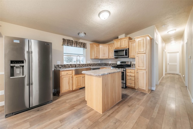 kitchen with light wood finished floors, light brown cabinets, a center island, stainless steel appliances, and a sink