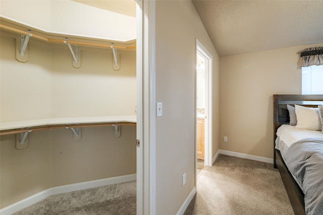 bedroom featuring a textured ceiling, lofted ceiling, baseboards, and light carpet