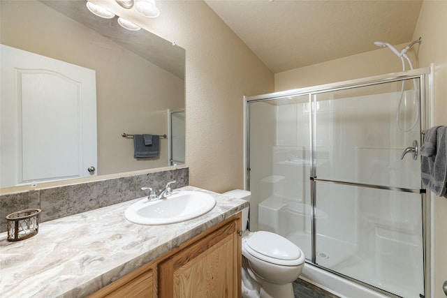 bathroom with toilet, a stall shower, vanity, and a textured wall