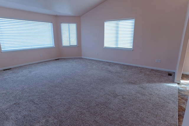 carpeted spare room featuring visible vents, baseboards, and lofted ceiling