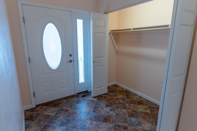 foyer with stone finish floor, baseboards, and a wealth of natural light