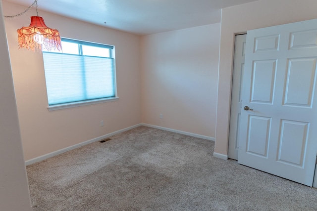 unfurnished room with carpet, visible vents, and baseboards