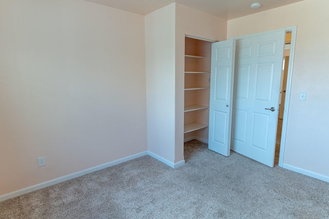 unfurnished bedroom featuring baseboards and light carpet