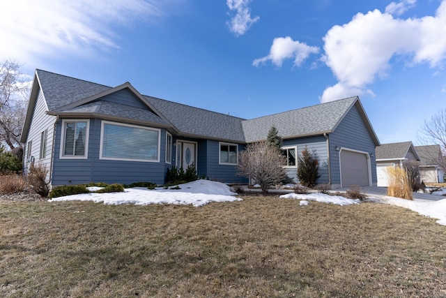 ranch-style house featuring a yard, a garage, and roof with shingles