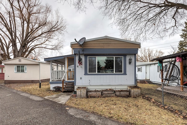 manufactured / mobile home featuring a porch and fence