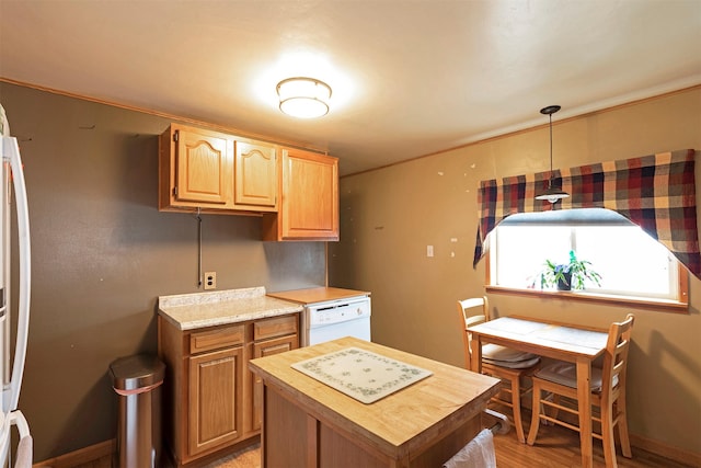 kitchen featuring white dishwasher, butcher block countertops, light wood-style floors, pendant lighting, and a center island