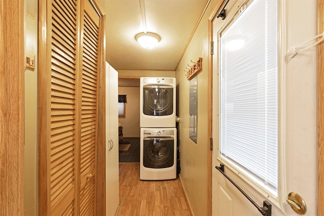 clothes washing area with stacked washer / dryer, light wood-style flooring, and laundry area