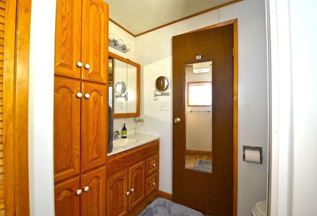 bathroom with toilet, vanity, and crown molding