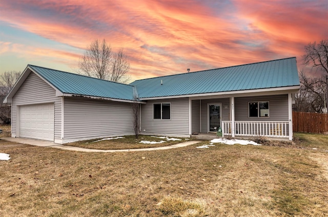 view of front of property with fence, an attached garage, covered porch, a lawn, and metal roof