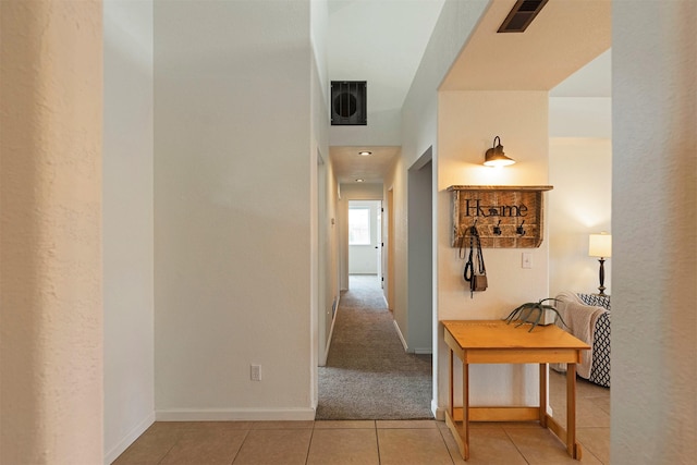 hall featuring tile patterned floors, baseboards, visible vents, and carpet floors