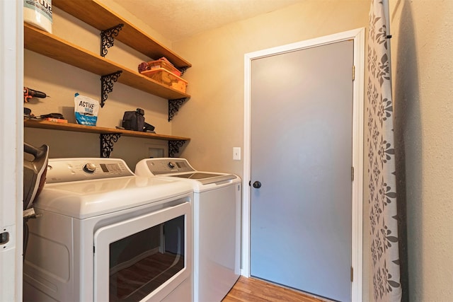 washroom featuring light wood-style flooring, washing machine and dryer, and laundry area