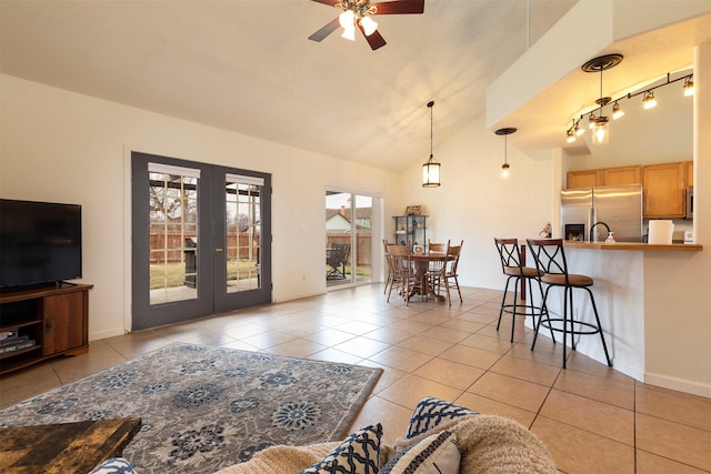 living area featuring french doors, light tile patterned floors, baseboards, ceiling fan, and vaulted ceiling