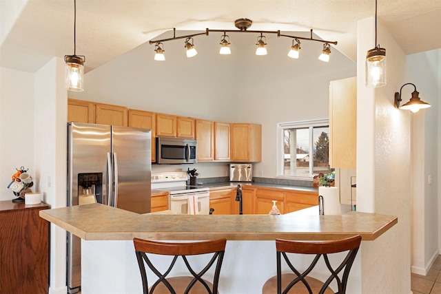 kitchen featuring pendant lighting, light brown cabinetry, a peninsula, appliances with stainless steel finishes, and a breakfast bar area