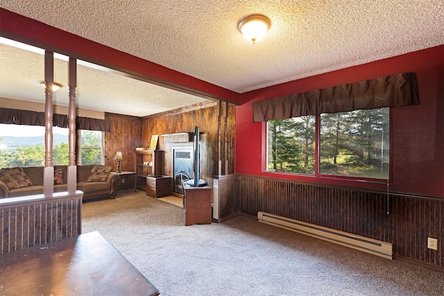 unfurnished living room featuring beam ceiling, a textured ceiling, wooden walls, carpet, and baseboard heating