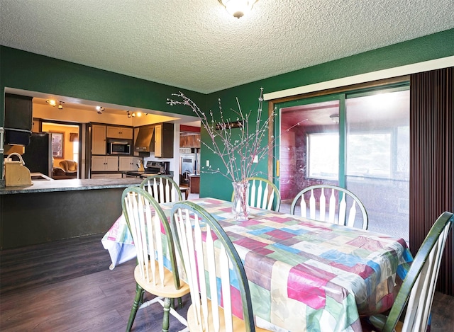 dining area featuring a textured ceiling, dark wood finished floors, and wallpapered walls