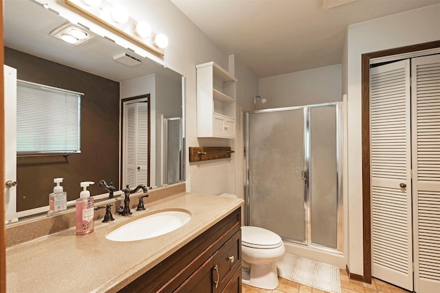 bathroom with a closet, toilet, a stall shower, and vanity