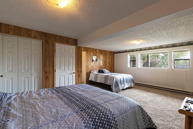 carpeted bedroom featuring a baseboard heating unit, a textured ceiling, a closet, and wood walls