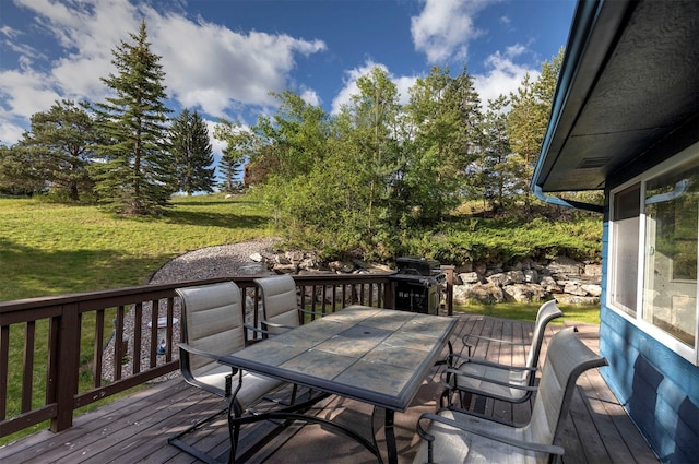 wooden terrace featuring outdoor dining area, a yard, and grilling area