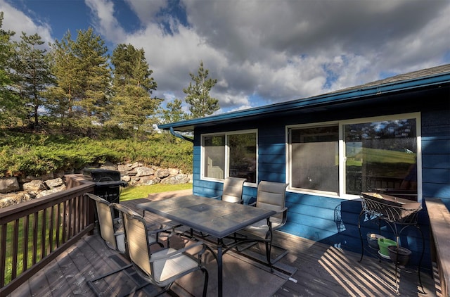 deck with outdoor dining space and a grill