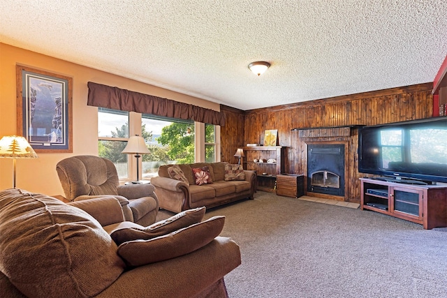 carpeted living area with wooden walls, a fireplace with flush hearth, and a textured ceiling