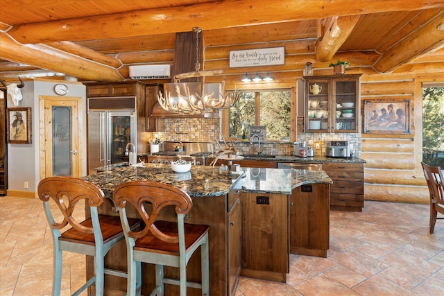 kitchen with beam ceiling, an island with sink, appliances with stainless steel finishes, wooden ceiling, and decorative backsplash