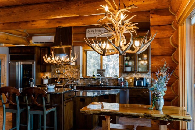 kitchen with a sink, a wall mounted air conditioner, built in fridge, stainless steel dishwasher, and a notable chandelier