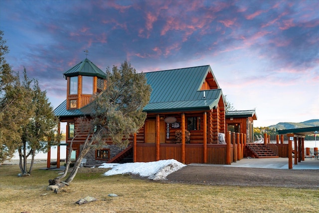 view of front of property featuring a porch, log exterior, metal roof, and a standing seam roof