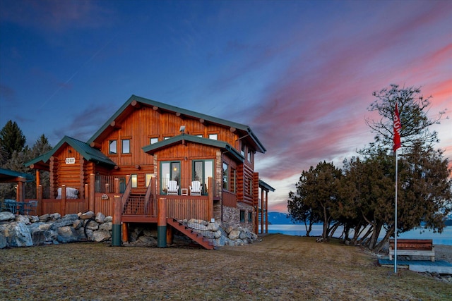 back of house at dusk featuring stairs and log exterior