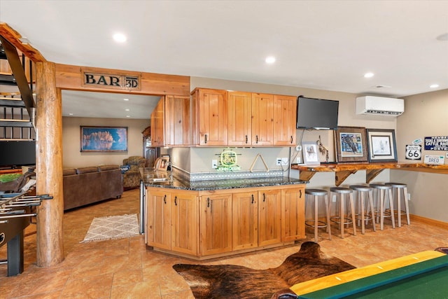 kitchen featuring a wall mounted air conditioner, baseboards, a kitchen breakfast bar, and recessed lighting