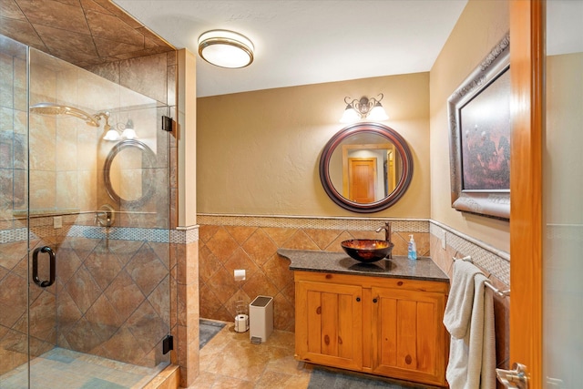 full bathroom featuring vanity, tile walls, a shower stall, and wainscoting