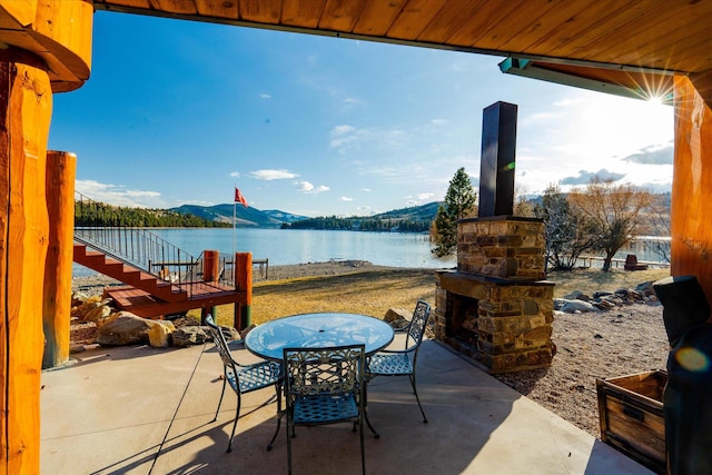 view of patio with a water and mountain view and outdoor dining space