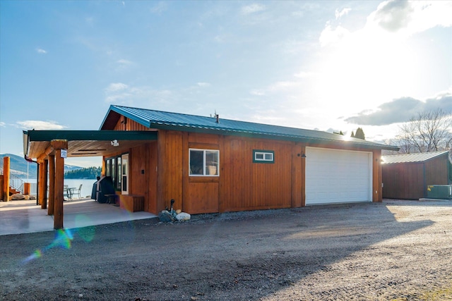 view of home's exterior featuring a garage, dirt driveway, and metal roof