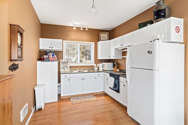 kitchen with visible vents, a sink, dark countertops, white cabinetry, and white appliances