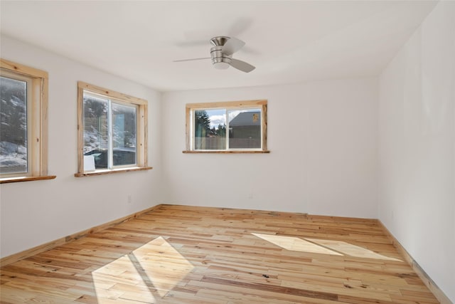 empty room with baseboards, wood finished floors, and a ceiling fan