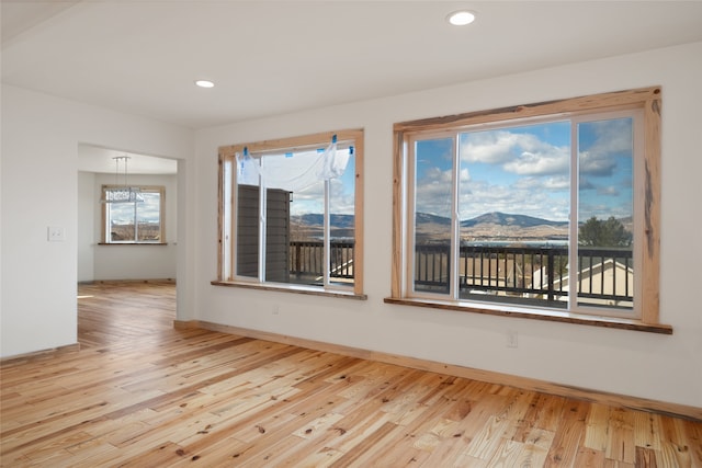 unfurnished room with recessed lighting, a mountain view, and wood finished floors