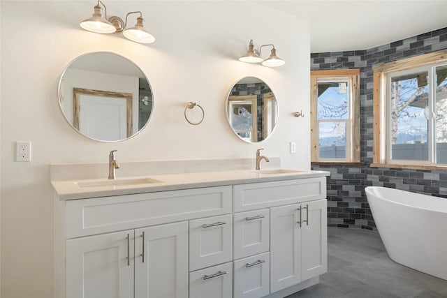 bathroom featuring a freestanding bath, tile walls, double vanity, and a sink