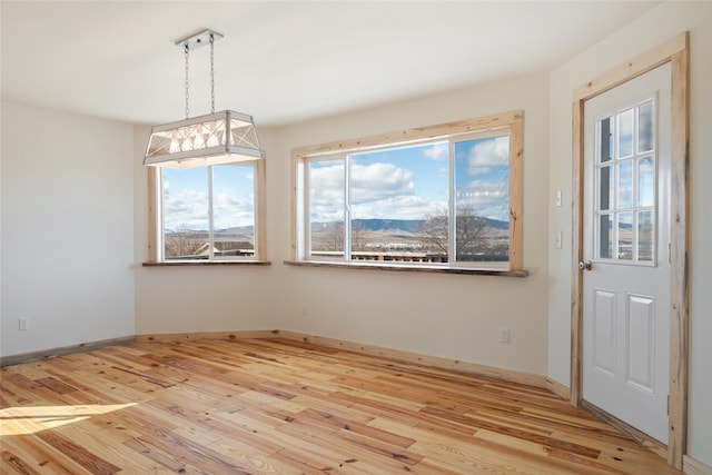 unfurnished dining area with light wood-type flooring and baseboards