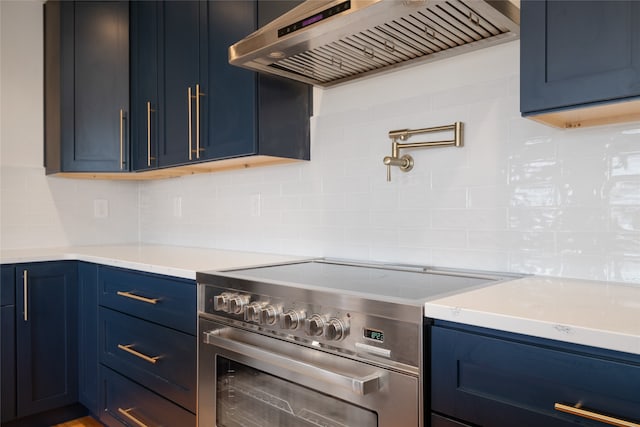 kitchen with tasteful backsplash, blue cabinets, custom range hood, and high end stainless steel range