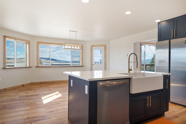 kitchen featuring light wood-style flooring, a sink, plenty of natural light, appliances with stainless steel finishes, and light countertops