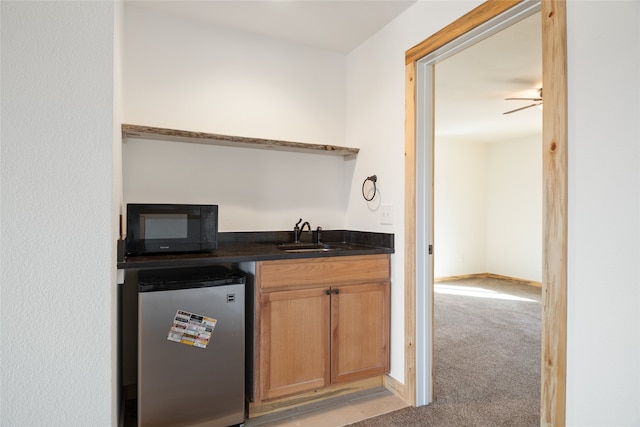 bar with black microwave, light colored carpet, freestanding refrigerator, a ceiling fan, and a sink