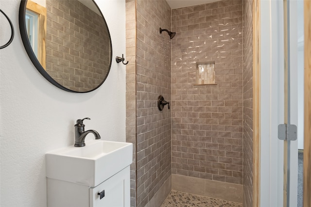 bathroom with a tile shower and vanity