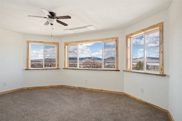 spare room featuring carpet flooring, baseboards, a mountain view, and ceiling fan