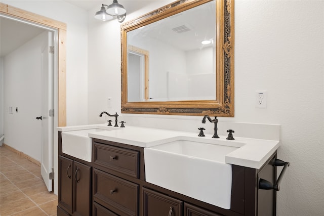 full bath featuring a sink, visible vents, double vanity, and tile patterned floors